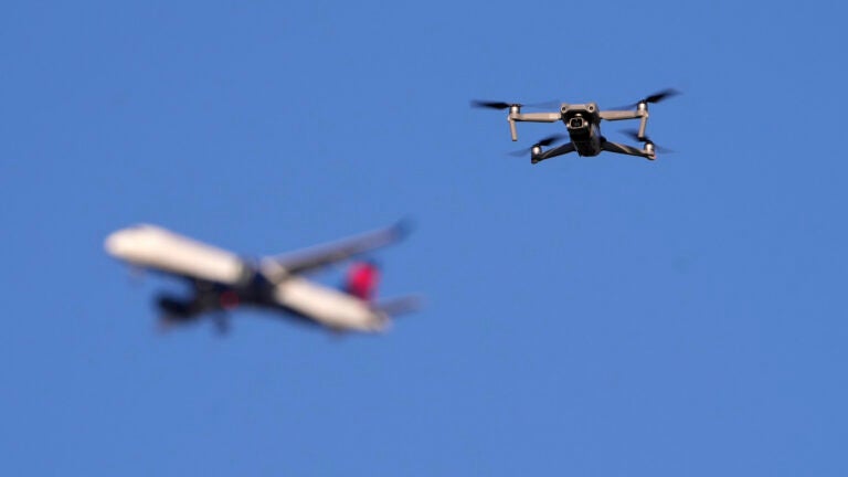 FILE - A drone hovers in airspace outside the safety perimeter surrounding St. Louis Lambert International Airport as an airliner approaches for a landing on March 10, 2025.