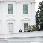 President Donald Trump gestures as he walks along the roof of the West Wing of the White House.