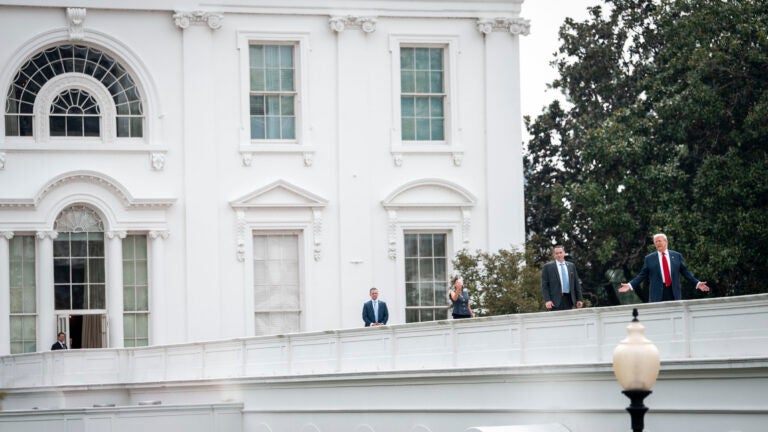 President Donald Trump gestures as he walks along the roof of the West Wing of the White House.